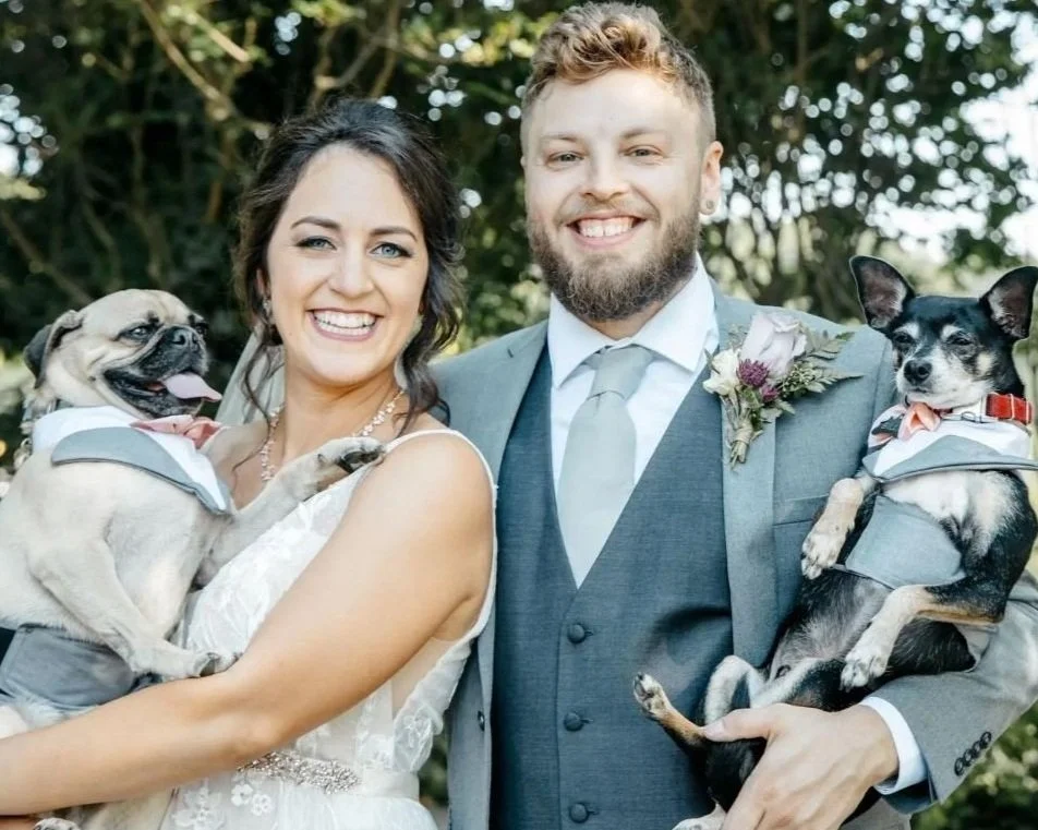 Ash and Amanda on their wedding day, each holding one of their own dogs
